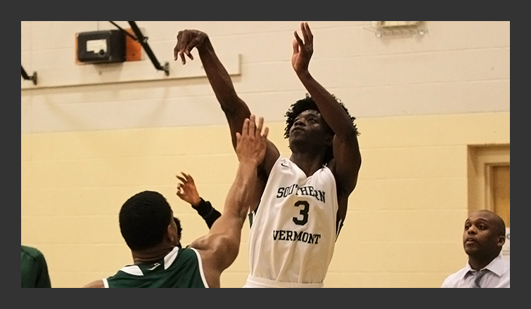 kajuan kinsey follows through on a shot with a newbury player's hand in his face; coach johnson in background watching